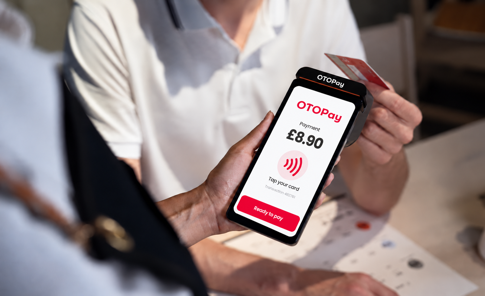 An OTO card payment terminal on a counter, ready for contactless payment